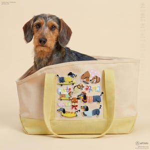 May include: A tan tote bag with yellow accents and handles, featuring dachshund dog patches and the text "Cute as Good". A brown and black dachshund dog sits inside the bag.