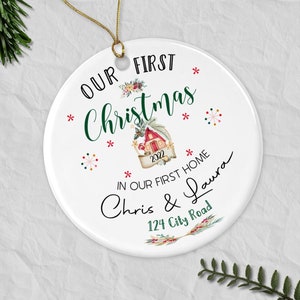 May include: White ceramic Christmas ornament with the text "Our First Christmas 2022 In Our First Home Chris & Laura 124 City Road". The ornament features a small house illustration with a red roof and green trim.