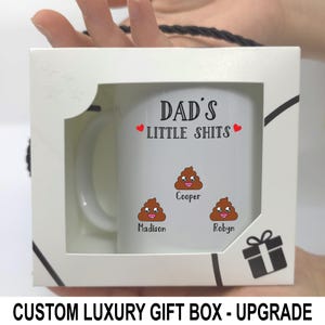 May include: A white ceramic mug inside a white gift box with a window. The mug features the text DAD'S LITTLE SHITS in black, two red hearts, and three brown poop emojis with smiling faces, each labeled with the names Cooper, Madison, and Robyn.