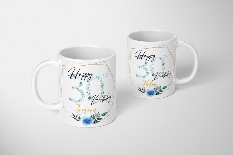 Może przedstawiać: Dwa białe ceramiczne kubki z złotymi geometrycznymi ramkami i niebieskimi wzorami kwiatowymi. Kubki m&oacute;wią "Happy 30th Birthday" z imieniem, "Jessica" i "Helen".
