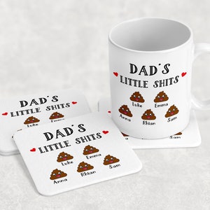 May include: A white ceramic mug and two square coasters featuring the text DAD'S LITTLE SHITS in black, two small red hearts, and five brown cartoon poop emojis with smiling faces, each labeled with the names Luke, Emma, Anna, Rhian, and Sam.