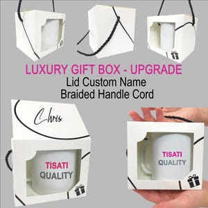 May include: A white cardboard gift box with a window, containing a white mug labeled TISATI QUALITY. The box features a black braided handle cord, a custom name Chris on the lid, and a small gift icon. Text reads LUXURY GIFT BOX - UPGRADE.