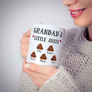 May include: White ceramic mug with the text "Grandad's Little Shits" and a heart on each side.  The mug has five cartoon poop emojis with names below each: Anna, Luke, Rhian, Emma, and Sam.