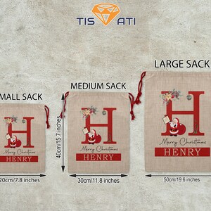 May include: Three burlap Christmas gift sacks with red and white trim, featuring a large red letter "H" with a Santa Claus illustration and the text "Merry Christmas" and a name. The sacks are labeled "Small Sack" (31 cm x 20 cm), "Medium Sack" (40 cm x 30 cm), and "Large Sack" (66 cm x 50 cm).