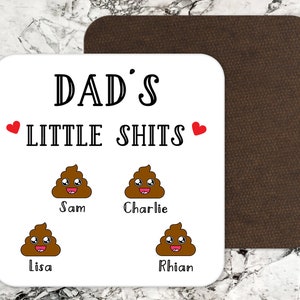 May include: A square white coaster with rounded corners featuring the black text DAD'S LITTLE SHITS, two red hearts, and four brown cartoon poop emojis with smiling faces. Below each emoji are the names Sam, Charlie, Lisa, and Rhian in black.