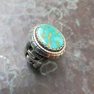 May include: A silver ring with a turquoise stone set in a bezel setting. The ring has a textured band.