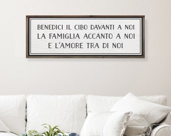 May include: A white wooden sign with black text that reads "BENEDICI IL CIBO DAVANTI A NOI LA FAMIGLIA ACCANΤΟ A NOI E L'AMORE TRA DI NOI".