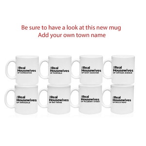 May include: Eight white coffee mugs with black text that reads "The Real Housewives of" followed by the name of a town. The towns are Hammonton, Fairfield, East Hanover, Arthur Avenue, Annandale, Bay Ridge, Mulberry Street, and Bulls Head.