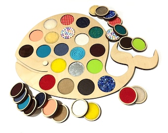 Puede incluir: Juguete de madera con forma de ballena con 20 círculos coloridos, cada uno con una textura diferente. Los círculos son extraíbles y se pueden emparejar con los agujeros correspondientes en la ballena.