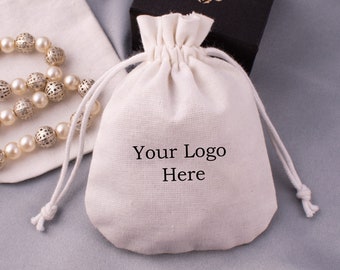 May include: A white cotton drawstring bag with the text "Your Logo Here" printed on the front.