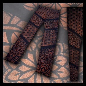 May include: A pair of black leggings with a brown mandala pattern. The leggings are made of a soft, stretchy fabric and are perfect for yoga, Pilates, or everyday wear.