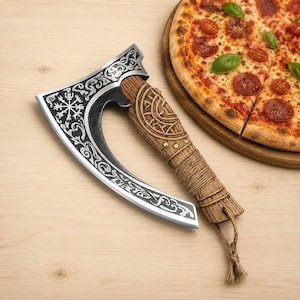 Può includere: Una rotella tagliapizza a forma di ascia da battaglia con una lama in metallo curva caratterizzata da intricati motivi argentati e un simbolo Vegvisir. Il manico è in legno marrone testurizzato con motivi circolari intagliati, piccoli borchie in ottone e un laccio in iuta.