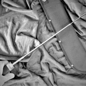 May include: A black and silver machete with a black nylon sheath. The machete is partially visible in the sheath, with the handle and blade extending out.