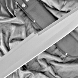 May include: A large, silver, single-edged blade with a black leather sheath. The blade is curved and has a sharp point. The sheath has a snap closure and is decorated with stitching.