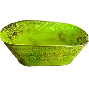 May include: A bright green, oval-shaped metal planter with a distressed finish. The planter features a textured surface with a dotted pattern and decorative floral designs along the rim. The planter is suitable for indoor or outdoor use.