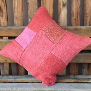 May include: A red and pink patchwork throw pillow with a square pattern. The pillow is made of a soft, textured fabric.