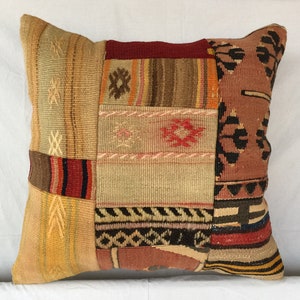 May include: A patchwork pillow cover with a variety of colors and patterns, including red, brown, beige, and black. The pillow cover is made of woven fabric and has a rectangular shape.