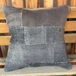 May include: A gray patchwork pillow with a square pattern. The pillow is made of a soft, woven fabric and has a slightly distressed look.