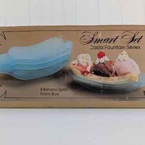 May include: A box set of four frosty blue banana split dishes. The box features an image of a banana split with ice cream and a set of empty dishes. Text on the box reads "Smart Set Coda Fountain Series" and "4 Banana Splits Frosty Blue."