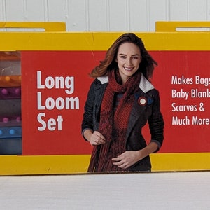 May include: A yellow box set labeled "Long Loom Set" by Boye, featuring a woman wearing a scarf. The box includes a scarf sample, looms, a hook, and a needle. The set is designed for making bags, blankets, and scarves.