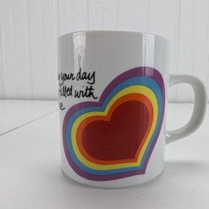 May include: White ceramic mug with a rainbow heart design and the text "May your days be filled with love".