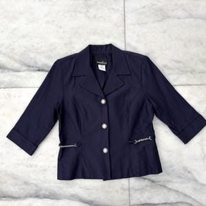 May include: A navy blue blazer with a silver chain detail and button closures.