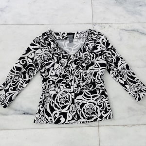 May include: Black and white floral print blouse with a V-neck and 3/4 sleeves.
