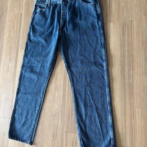 May include: A pair of blue denim jeans with a classic five-pocket design. The jeans have a straight leg cut and a button and zipper closure. The denim has a medium wash with subtle fading and wear.