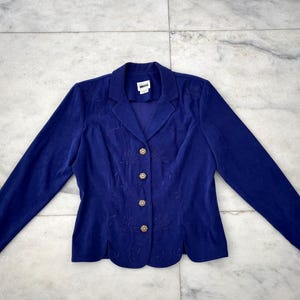 May include: A dark blue blazer with gold buttons and embroidered details. The blazer has a notched collar and long sleeves.