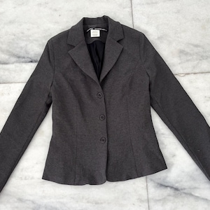 May include: A dark gray blazer with a notched collar and four buttons down the front.