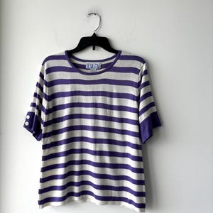 May include: A white and purple striped short-sleeved shirt with a small blue label that says "BRW" on the front.