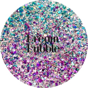 May include: A close-up of iridescent glitter in a variety of colors, including teal, purple, pink, and white. The glitter is arranged in a circular pattern and the text "Dream Bubble" is printed in black in the center of the glitter.