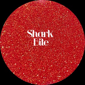 May include: Red glitter with the text "Shark Bite" in white.