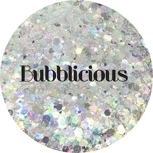 May include: A close-up of iridescent glitter in various sizes and shapes. The glitter is white with a rainbow sheen. The word "Bubblicious" is printed in black letters on the glitter.