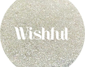 May include: A white glitter background with the word "Wishful" written in white text.