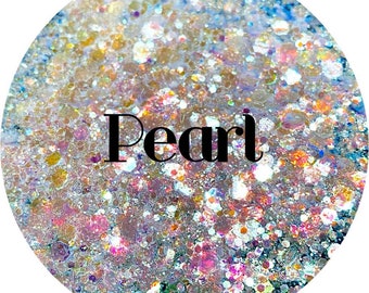 May include: A close-up of iridescent glitter with a variety of colors, including gold, silver, pink, and blue. The glitter is arranged in a circular pattern and the word "Pearl" is written in black text in the center of the image.