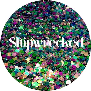 May include: A close-up of a round container filled with colorful glitter. The glitter is a mix of green, blue, purple, and gold. The word "Shipwrecked" is written in white letters across the glitter.