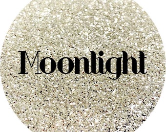 May include: A close-up of a silver glitter background with the word "Moonlight" in black text.