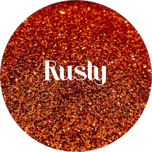 May include: A close-up of a jar of orange glitter with the word "Rusty" written in white letters on the front.