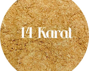May include: Close-up of a circular, textured surface with a golden hue. The text "14 Karat" is displayed in a white, elegant font across the surface. The overall appearance suggests a cosmetic product or material.