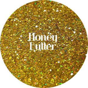 May include: A close-up of gold glitter with a holographic finish. The glitter is labeled "Honey Butter".