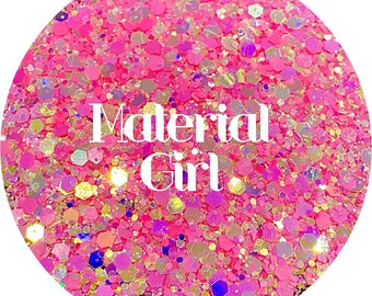 以下が含まれることがあります： ピンク、ゴールド、虹色のグリッターに、白い文字で「Material Girl」と書いてあります。