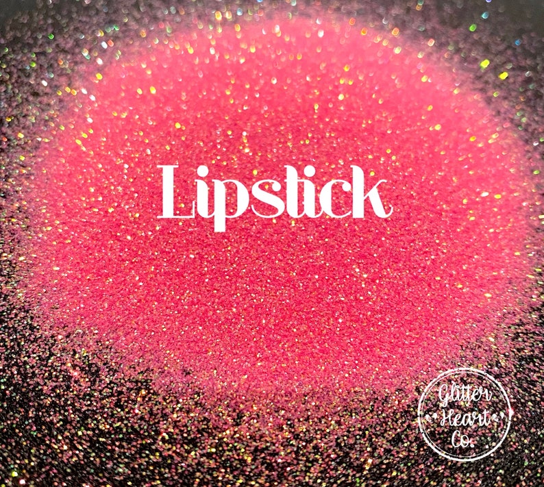 May include: A close-up of a pink glitter with iridescent shimmer. The glitter is labeled "Lipstick".