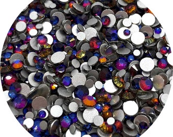 May include: A close-up view of a variety of iridescent rhinestones in assorted colors, including blue, purple, red, orange, and yellow. The rhinestones are scattered on a silver background.