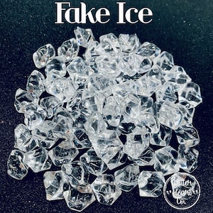 May include: A pile of clear plastic ice cubes, perfect for adding a touch of realism to your craft projects or decorations.  The ice cubes are scattered on a black background.  The text "Fake Ice" is written in white at the top of the image.