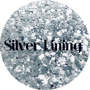 May include: Silver glitter with a white base. The glitter is in various sizes and shapes. The text "Silver Lining" is printed in black on the glitter.