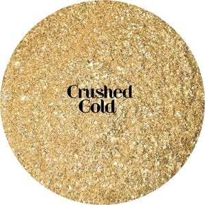 May include: A circular swatch of fine, reflective gold glitter particles with a dense, shimmering texture. The text "Crushed Gold" is printed in a bold, black serif font across the center of the golden, sparkling, granular surface.
