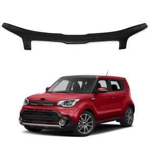 May include: A black hood deflector and a red Kia Soul car. The deflector is above the car and is curved. The car has black trim and silver wheels. The car is red.