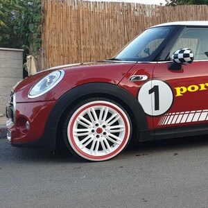 May include: A red Mini Cooper with a white roof and racing stripes. The car has a large number 1 on the side, along with the word "portaw" in yellow. The wheels are white with a red trim.