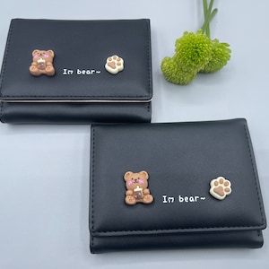 May include: Two black leather wallets with a brown bear and paw print design. The text "I'm bear~" is printed on both wallets.